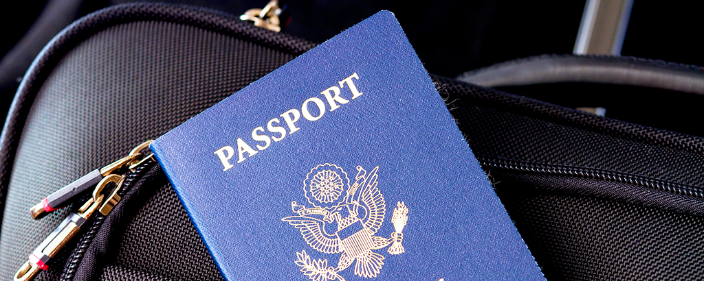 blue passport over a black suite case